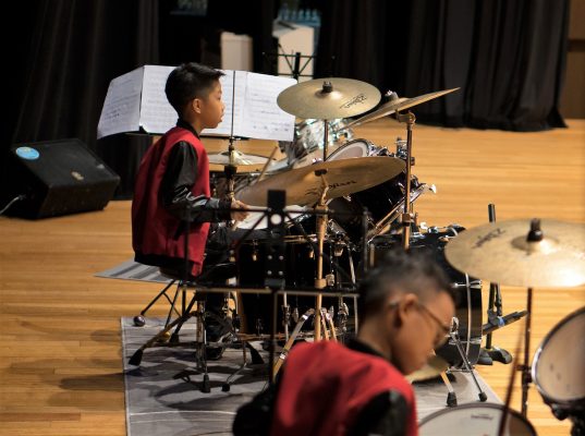 Fine Momentum music class drum set student playing the drums